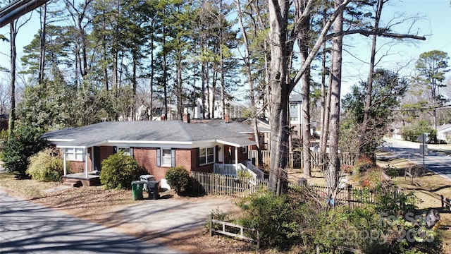 ranch-style house with driveway, a fenced front yard, and brick siding