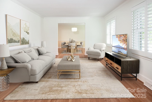 living area with crown molding, wood finished floors, baseboards, and visible vents