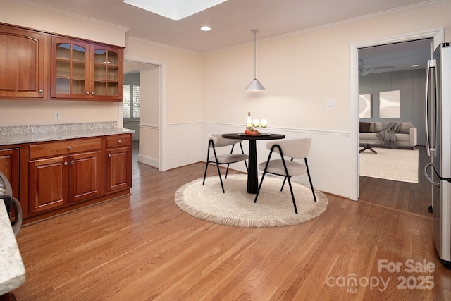 dining area with recessed lighting, a skylight, crown molding, and light wood finished floors