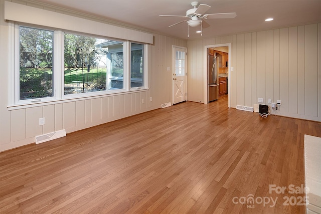 empty room with light wood-style flooring, visible vents, and ceiling fan