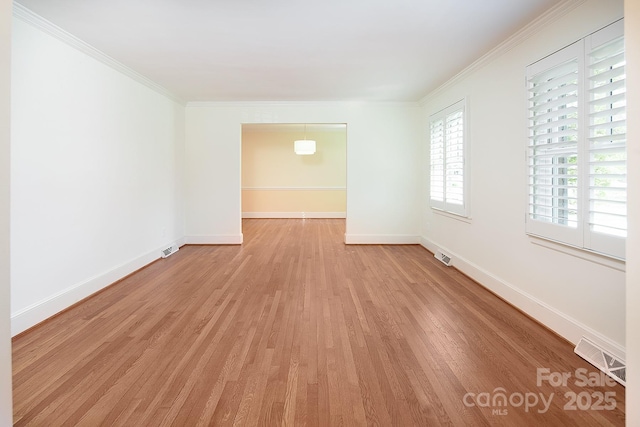 spare room with visible vents, baseboards, light wood-style floors, and ornamental molding