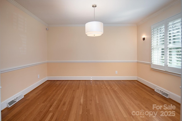 spare room with visible vents, crown molding, light wood-type flooring, and baseboards