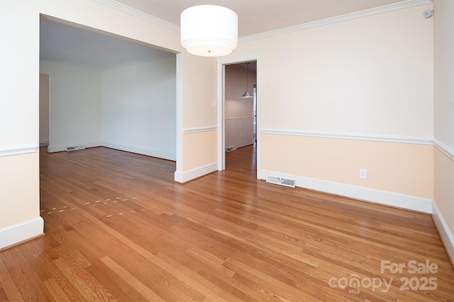 unfurnished room featuring visible vents, baseboards, wood finished floors, and crown molding