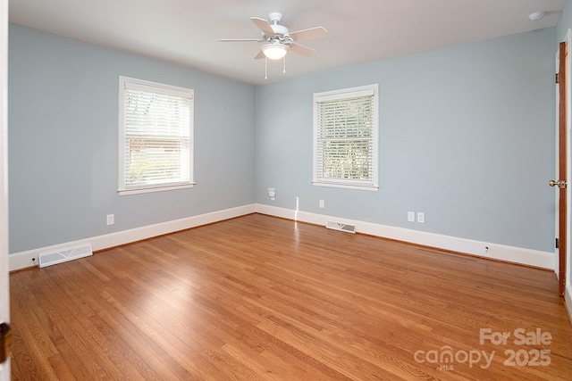 empty room with visible vents, baseboards, wood finished floors, and a ceiling fan