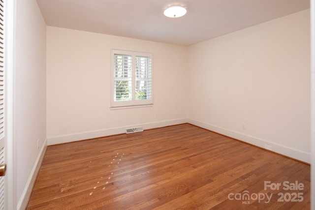 empty room featuring visible vents, baseboards, and wood finished floors