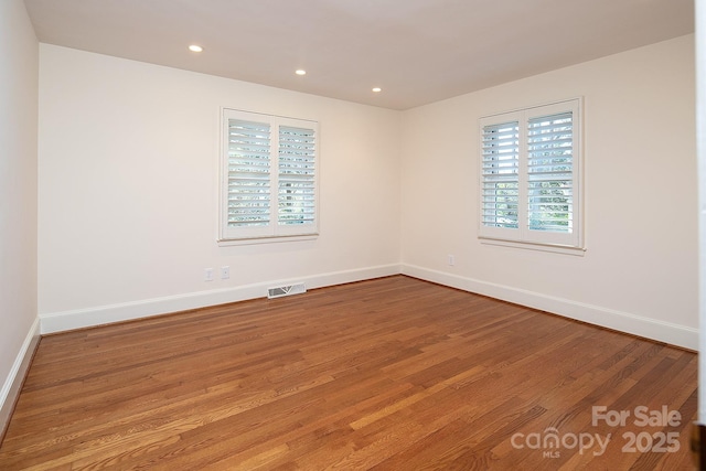 spare room featuring visible vents, recessed lighting, baseboards, and wood finished floors