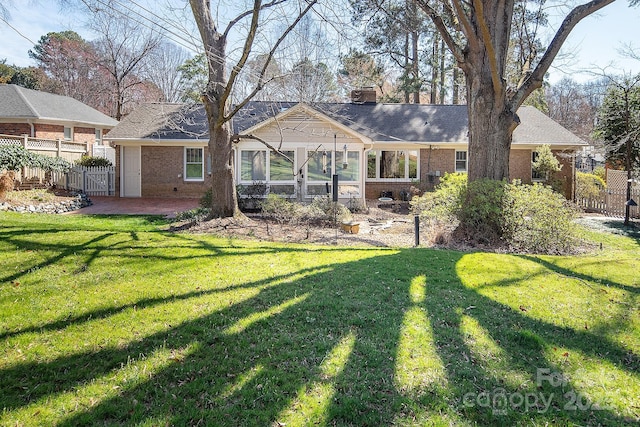 rear view of property with brick siding, a lawn, and a chimney