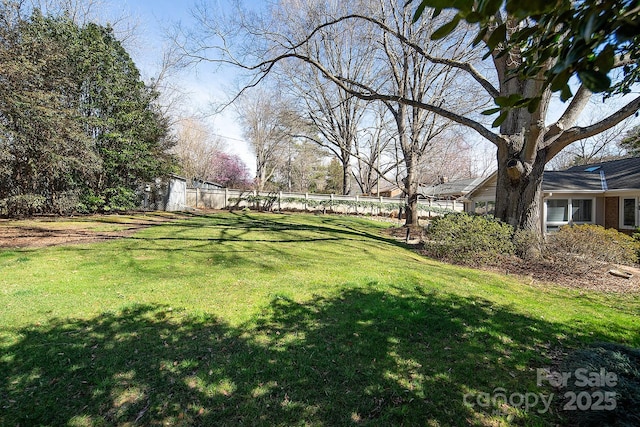 view of yard with a storage shed, an outbuilding, and fence