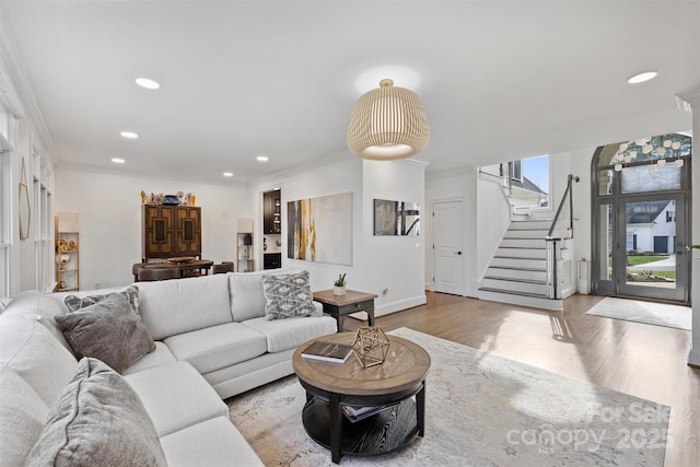 living area featuring recessed lighting, wood finished floors, crown molding, and stairs