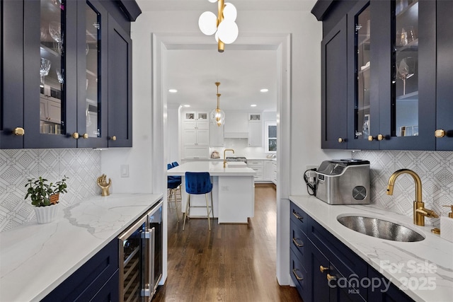 kitchen featuring dark wood-style floors, wine cooler, blue cabinetry, hanging light fixtures, and a sink