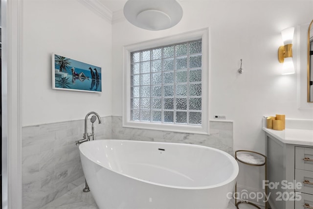 full bathroom with a freestanding tub, a wainscoted wall, vanity, tile walls, and ornamental molding