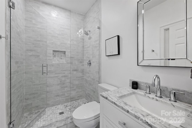 bathroom featuring a shower stall, toilet, and vanity