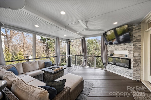 sunroom featuring ceiling fan and a fireplace