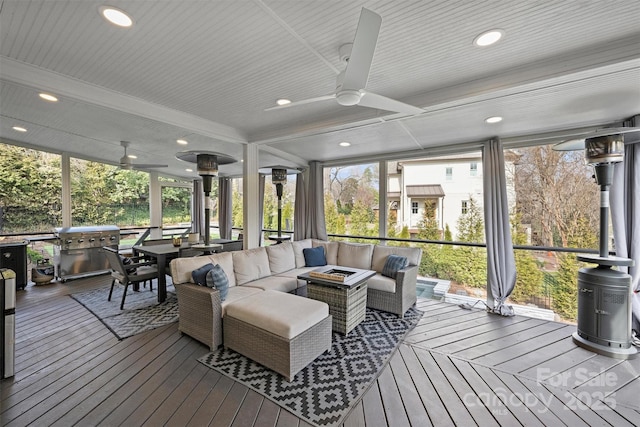 sunroom with beamed ceiling, plenty of natural light, and a ceiling fan