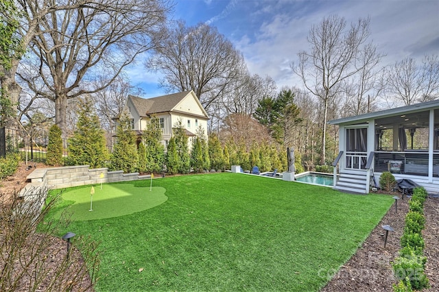 view of yard with a sunroom and an outdoor pool