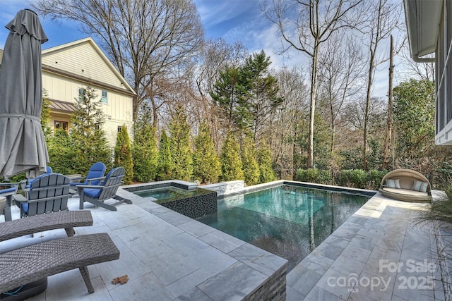 pool with an in ground hot tub and a patio