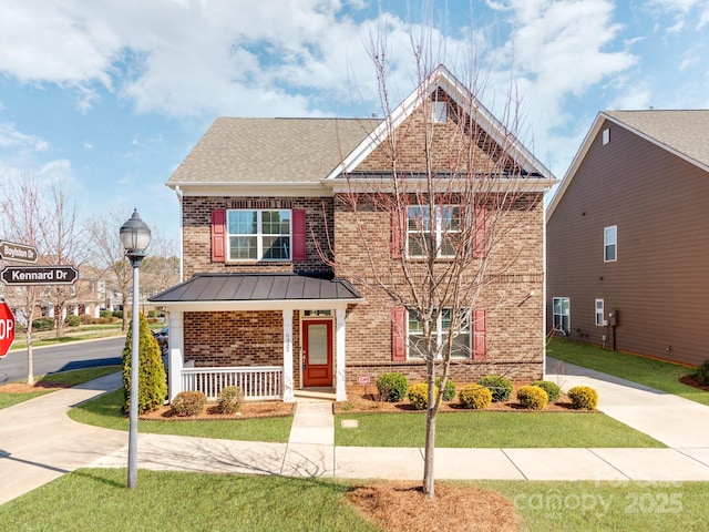 view of front of property with brick siding, covered porch, a front yard, a standing seam roof, and metal roof