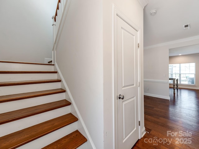 staircase with baseboards, wood finished floors, visible vents, and crown molding