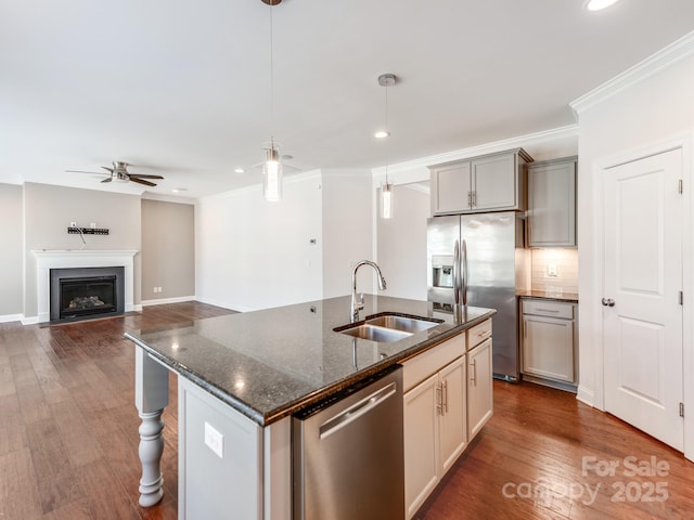 kitchen with dark wood-style floors, a fireplace with flush hearth, appliances with stainless steel finishes, crown molding, and a sink