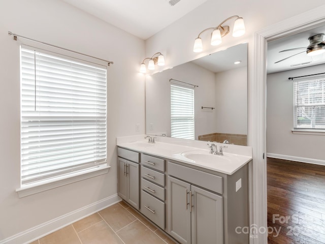 bathroom with double vanity, visible vents, a ceiling fan, a sink, and baseboards