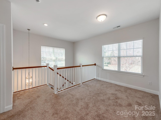 carpeted empty room featuring visible vents and baseboards