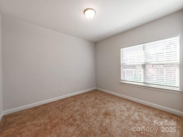 spare room with light carpet and baseboards