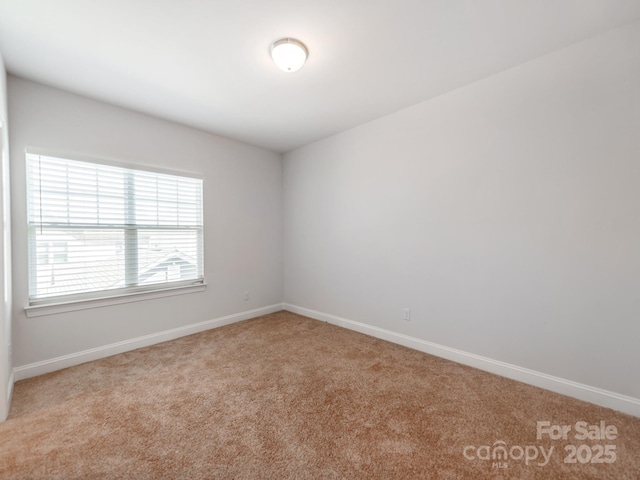 spare room featuring carpet flooring and baseboards