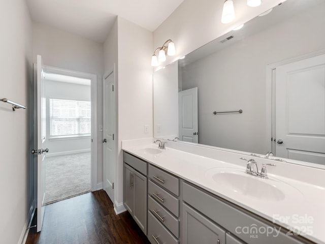 bathroom with double vanity, baseboards, visible vents, and a sink