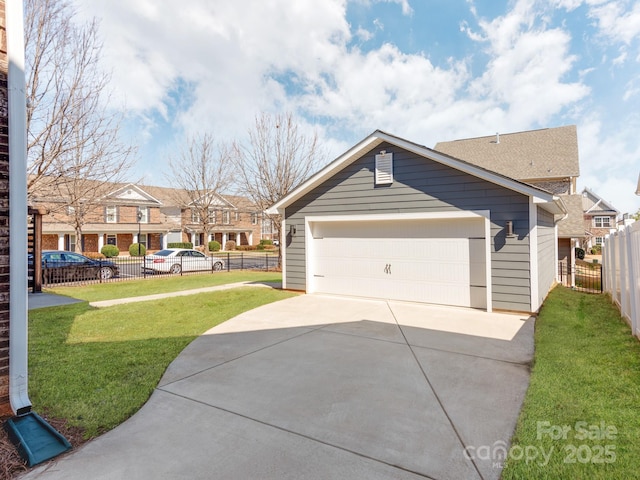 exterior space featuring a detached garage, a residential view, fence, and a lawn