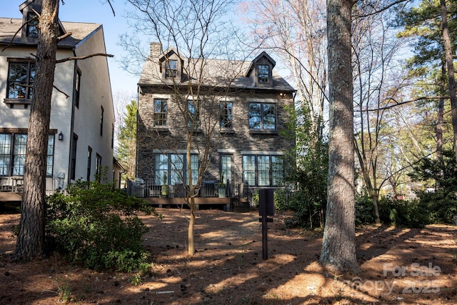 rear view of house featuring a chimney and a wooden deck