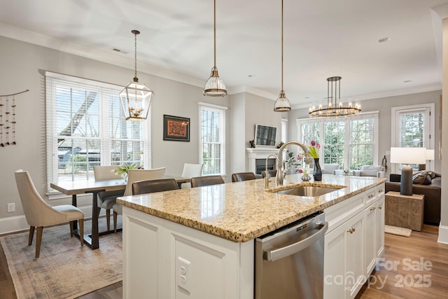 kitchen with open floor plan, dishwasher, light wood-type flooring, a fireplace, and a sink