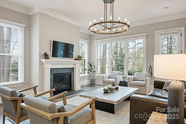 living room with baseboards, a glass covered fireplace, and crown molding