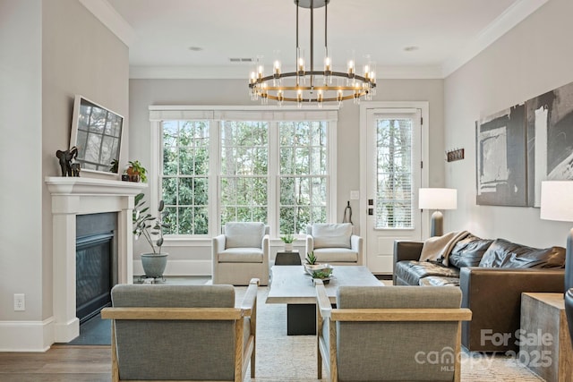 living area featuring a glass covered fireplace, wood finished floors, baseboards, and ornamental molding