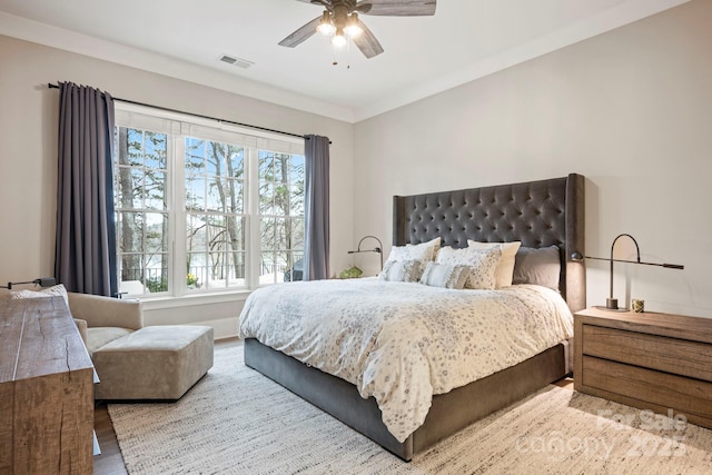 bedroom featuring visible vents, ornamental molding, ceiling fan, and wood finished floors