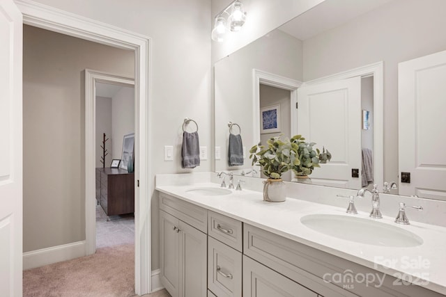 full bath with a sink, baseboards, and double vanity