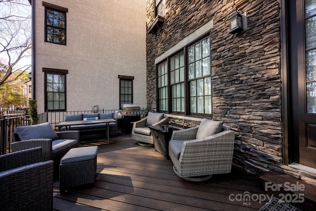 wooden terrace featuring an outdoor living space and area for grilling