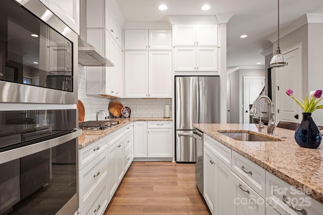 kitchen featuring light wood-style flooring, recessed lighting, stainless steel appliances, a sink, and tasteful backsplash