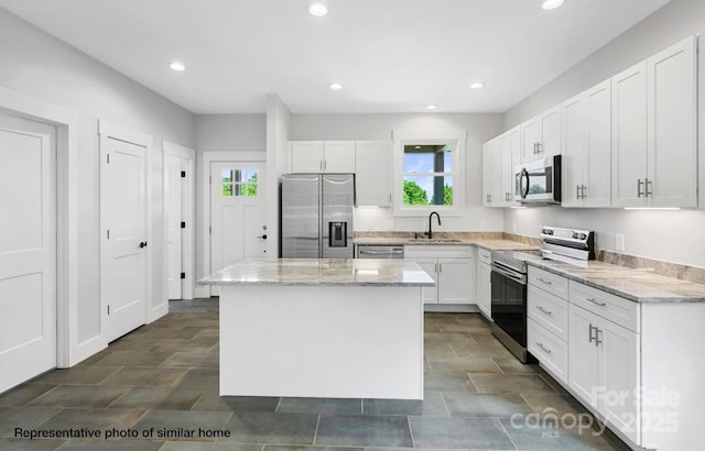 kitchen featuring stainless steel appliances, a sink, a center island, white cabinets, and light stone countertops