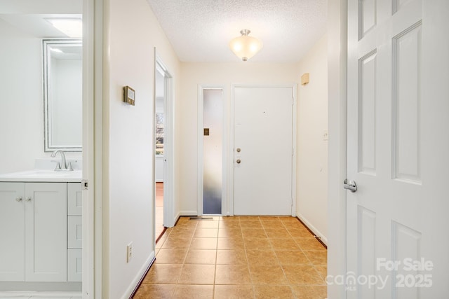 entrance foyer featuring light tile patterned floors, baseboards, and a textured ceiling