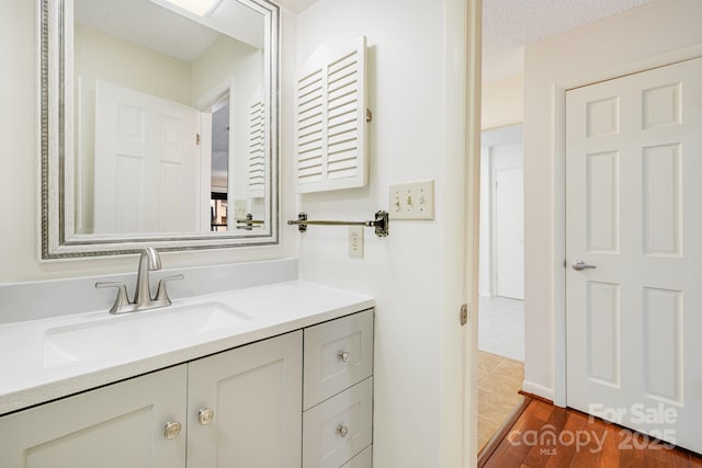 bathroom with vanity, wood finished floors, and a textured ceiling