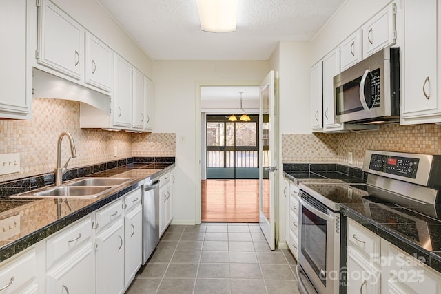 kitchen featuring a sink, appliances with stainless steel finishes, white cabinets, and tile countertops