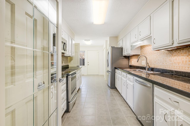 kitchen featuring a sink, dark countertops, appliances with stainless steel finishes, and light tile patterned floors