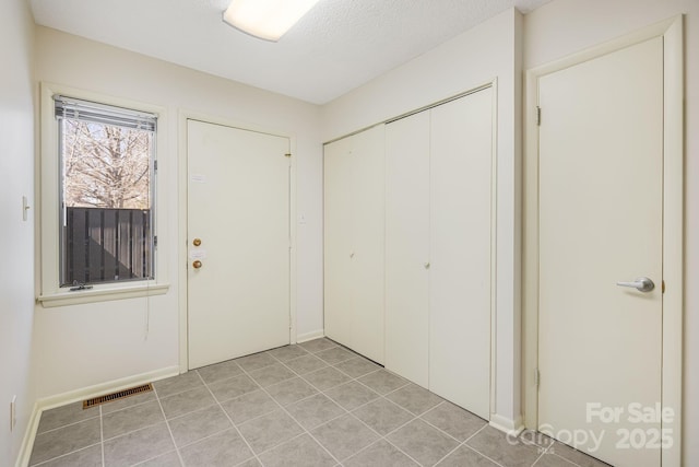 foyer featuring light tile patterned floors, visible vents, and a textured ceiling