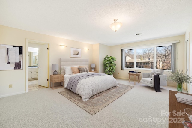 bedroom featuring visible vents, baseboards, a textured ceiling, light colored carpet, and connected bathroom