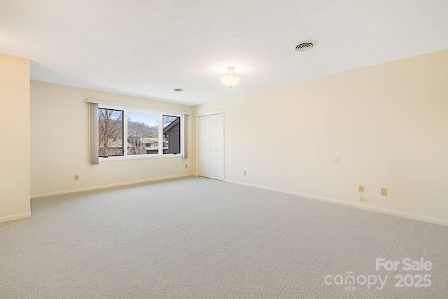 carpeted empty room with visible vents and baseboards