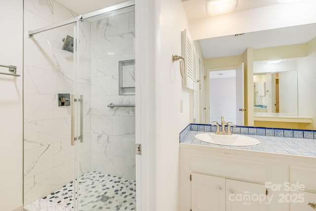 full bathroom featuring a marble finish shower and vanity