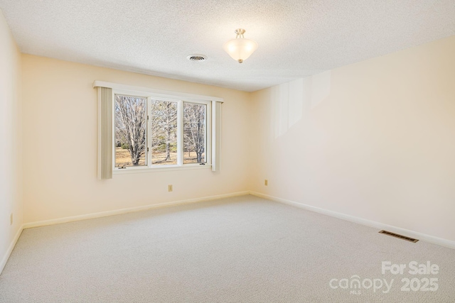 unfurnished room featuring visible vents, carpet floors, a textured ceiling, and baseboards