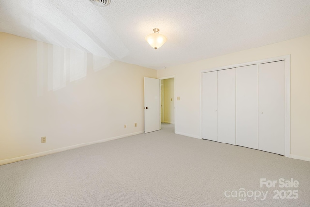 unfurnished bedroom with light carpet, baseboards, a closet, and a textured ceiling