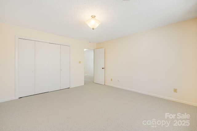 unfurnished bedroom with a closet, baseboards, a textured ceiling, and carpet