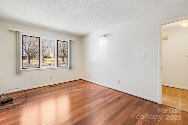 spare room with visible vents, a textured ceiling, and wood finished floors